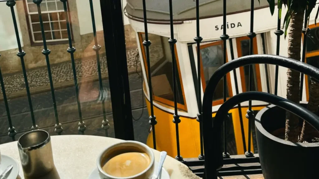 Mesa de café em uma varanda com vista para o elétrico tradicional passando nas ruas de Lisboa