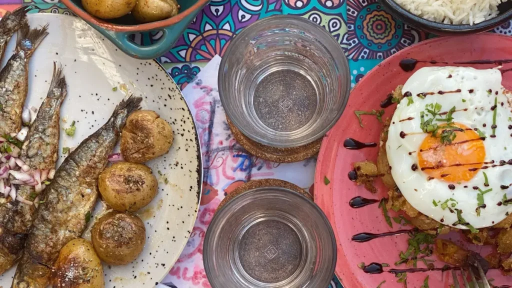 Mesa de restaurante em Lisboa servida com pratos salgados típicos como sardinhas assadas com batatas ao murro e bacalhau a brás