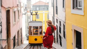 Mulher caminhando sozinha em ladeira com ascensor amarelo da Bica em Lisboa em guia de transporte público