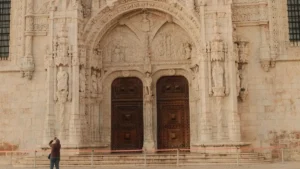 Fachada em estilo manuelino do Mosteiro dos Jerónimos em Belém com mulher contemplando a arquitetura em Lisboa