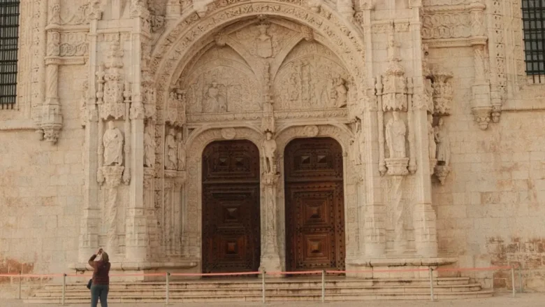 Fachada em estilo manuelino do Mosteiro dos Jerónimos em Belém com mulher contemplando a arquitetura em Lisboa