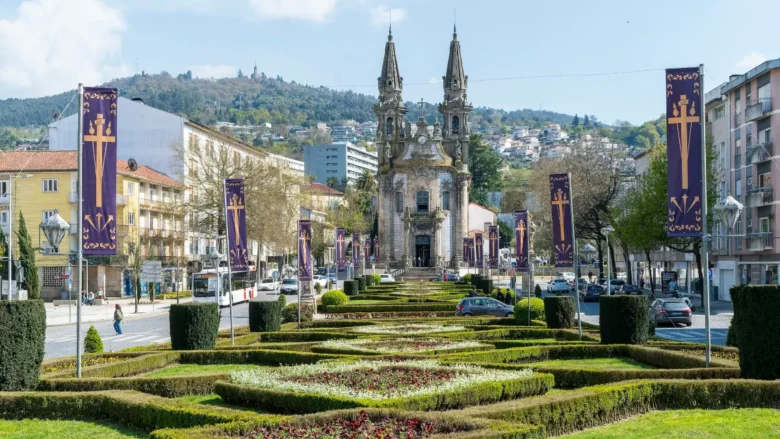 Jardins floridos do Largo de República do Brasil com a Igreja da Consolação ao fundo em Guimarães.