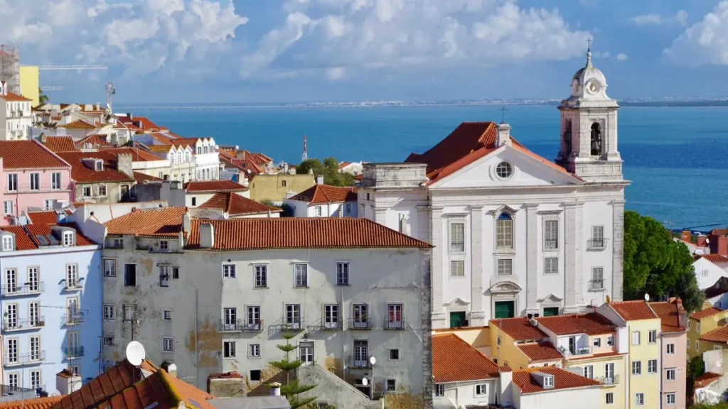 Vista panorâmica da Igreja de Santo Estêvão entre os telhados vermelhos de Alfama com o Rio Tejo ao fundo