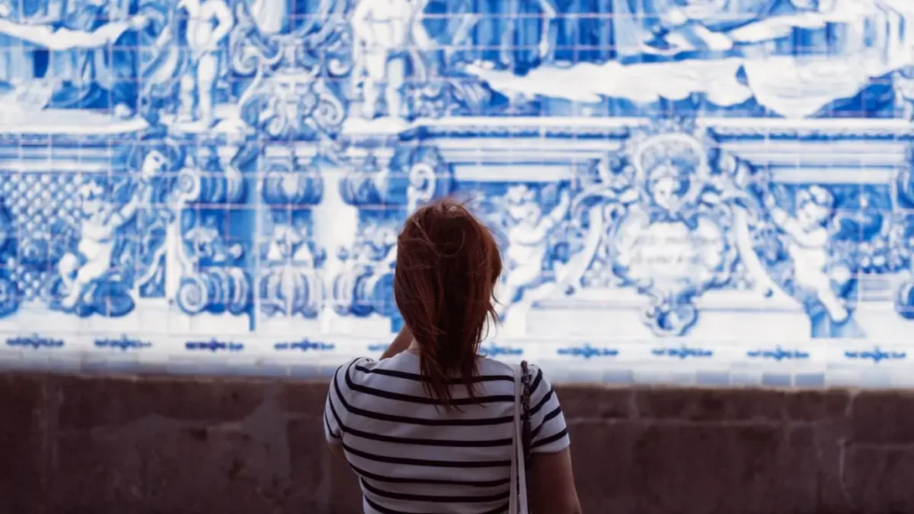Mulher de costas admirando grande painel de azulejos portugueses azuis e brancos no Museu do Azulejo em Lisboa