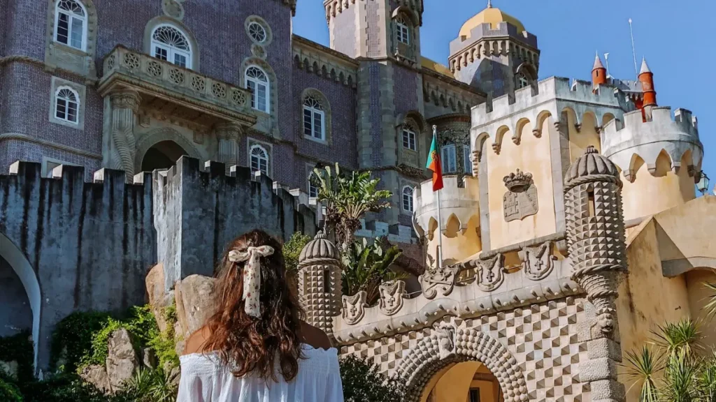Viajante solo observando a fachada histórica e os detalhes do Palácio da Pena em Sintra, Portugal.