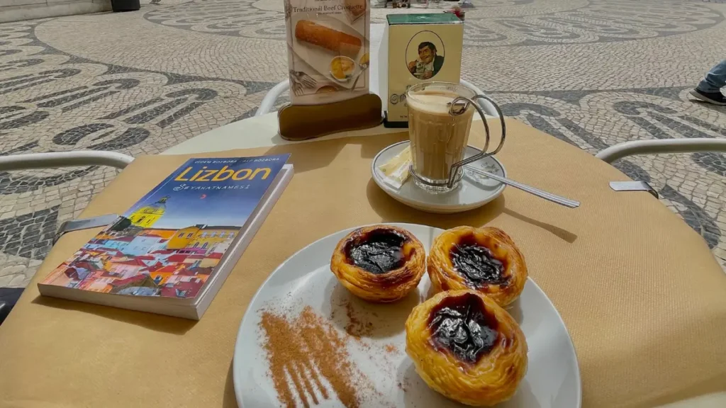 Mesa de café com pastéis de nata e guia de viagem Lizbon em roteiro em Belem Lisboa