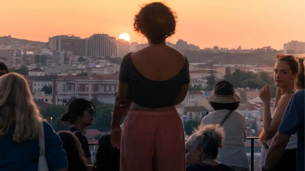 Pessoas reunidas admirando o pôr do sol em um miradouro de Lisboa, ilustrando a tranquilidade de viajar por Portugal
