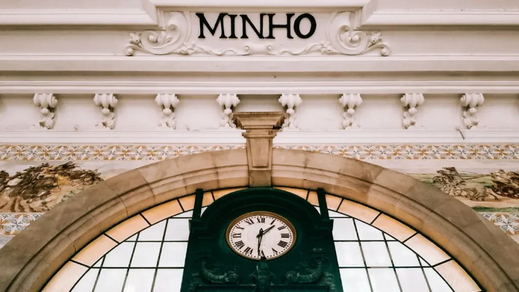 Relógio histórico com inscrições Minho e Porto e detalhes de azulejos na estação de trem.