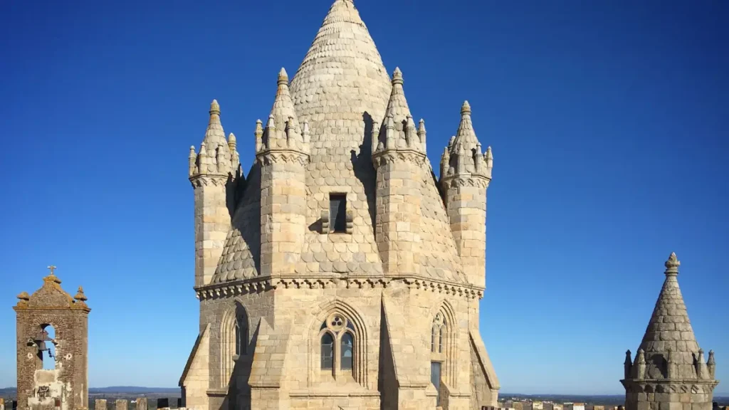 Torre lanterna em pedra da Sé Catedral de Évora vista do terraço sob céu azul.